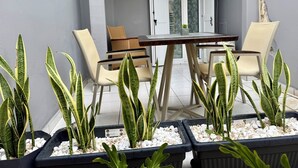 A patio with a table and chairs, surrounded by potted plants and a view of the interior. - DOM SUITES (Daratsos)