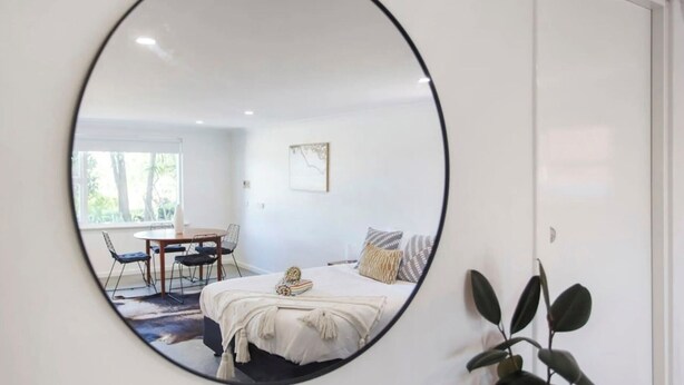 A bedroom with a bed, a bedside table, a chair, and a window. - Studio Escape (Hamilton Hill)