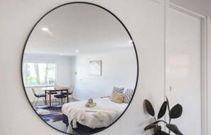 A bedroom with a bed, a bedside table, a chair, and a window.
