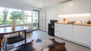 A modern kitchen with white cabinets, a black refrigerator, and a wooden countertop. - Studio Escape (Hamilton Hill)