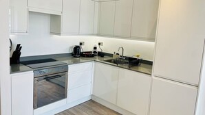 Een moderne keuken met witte kasten, een roestvrijstalen spoelbak en een ingebouwde oven.