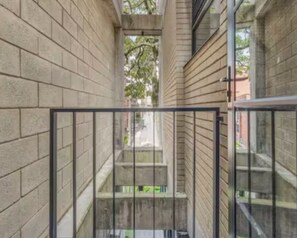 A narrow corridor with brick walls and a metal gate, leading to a staircase.