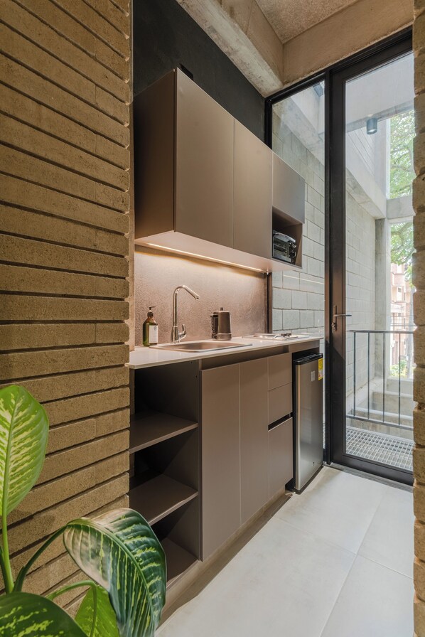A modern kitchen with a built-in oven, a sink, and a dishwasher. There is a window with a view of the outside. - Recinto68 (Medellín)