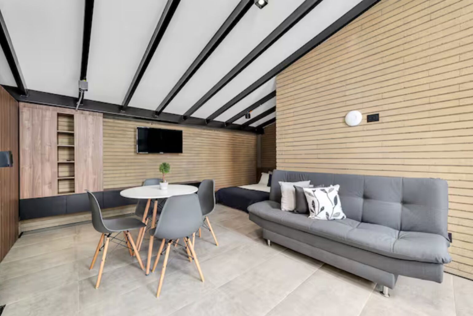 A modern interior with a grey sofa, round table, and chairs.