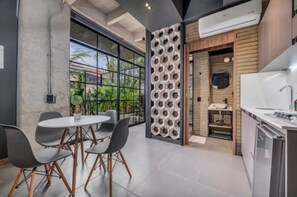 A modern kitchen with a built-in stove, a sink, and a dining area with a round table and chairs. - Recinto68 (Medellín)