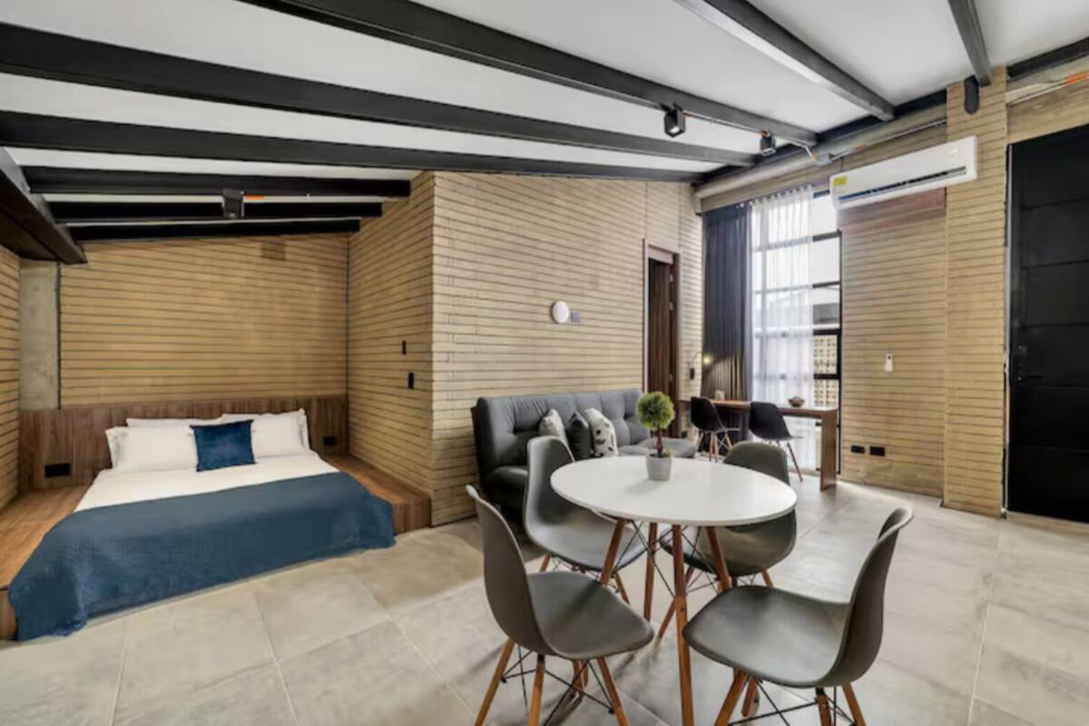 Une chambre d’hôtel moderne équipée d’un lit, d’un canapé, d’une table à manger avec des chaises et d’une grande fenêtre.