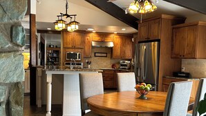 A spacious kitchen with wooden cabinets, a central island, and a dining area with a round table and chairs.