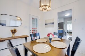 A dining area with a wooden table, four chairs, a vase with flowers, and a mirror on the wall. - The little refuge (Gatineau)