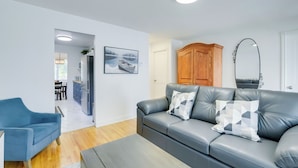Un salon moderne avec un canapé en cuir gris, un fauteuil bleu et un meuble en bois.
