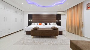 A modern bedroom with a large bed, a bench, and a wardrobe.