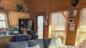 A cozy living room with a grey sofa, a round wooden coffee table, and a small potted plant.