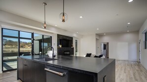Une cuisine moderne dotée d’un grand îlot central, d’appareils électroménagers intégrés et offrant une vue sur l’extérieur.