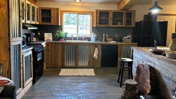 A kitchen with wooden cabinets, a central island, a black stove, and a window.