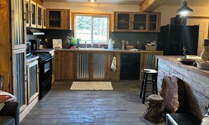 Una cocina con armarios de madera, una isla central, una estufa negra y un ventanal.
