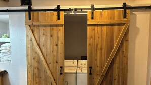A room with a wooden sliding barn door leading to a laundry area with washing machines.