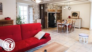 Una sala de estar acogedora con un sofá rojo, una mesa de comedor de madera y una pared de piedra.