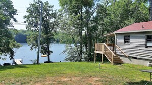 A cabin with a deck overlooking a lake, surrounded by trees. - Blue Loon Camp on Pleasant Pond in Litchfield (Litchfield)