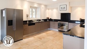 A modern kitchen with stainless steel appliances, a black countertop, and beige cabinetry.