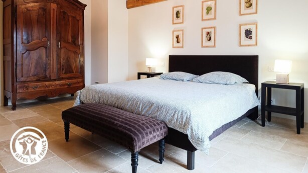 A bedroom with a bed, two bedside tables, a wooden wardrobe, and a bench.