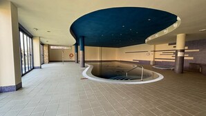 A large indoor swimming pool with a curved ceiling, tiled floor, and a lifeguard stand. - Charming 1-bedroom apartment with AC, WiFi and amazing views in Mojácar (Mojácar)