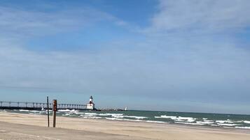 Un paysage côtier avec un phare, une jetée et un panneau indicateur.