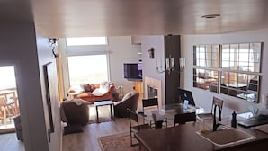 A modern living room with a fireplace, a television, and a dining area with a glass table.