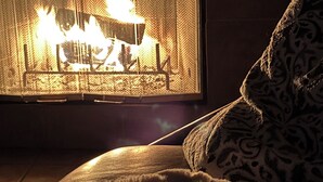 A room with a fireplace, a patterned throw pillow, and a blanket.
