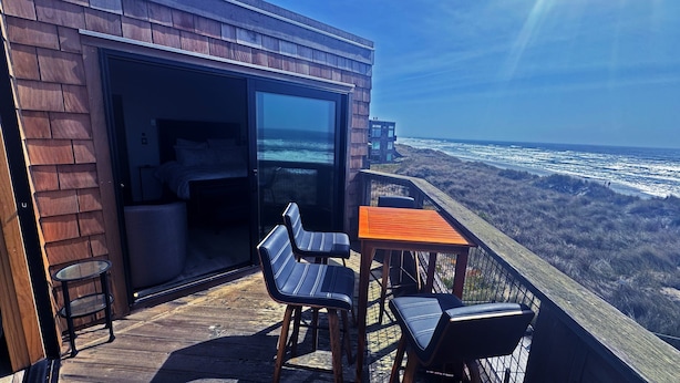 A deck with a table and chairs overlooking the ocean.