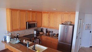 A modern kitchen with wooden cabinets, stainless steel appliances, and a granite countertop.