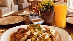 Zona pranzo con tavolo apparecchiato per un pasto, inclusi nachos, una bevanda e una pianta in vaso.