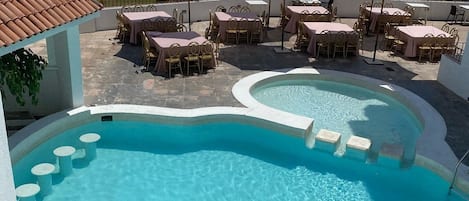 A pool area with lounge chairs and umbrellas, surrounded by palm trees.