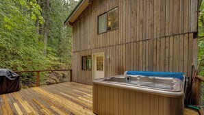 A wooden deck with a hot tub and a door leading to a cabin. - A 3 Story, 3 Bedroom Traditional Rustic Ski and Hiking Chalet (Deming)