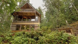 A wooden cabin with a balcony, surrounded by dense forest. - A 3 Story, 3 Bedroom Traditional Rustic Ski and Hiking Chalet (Deming)