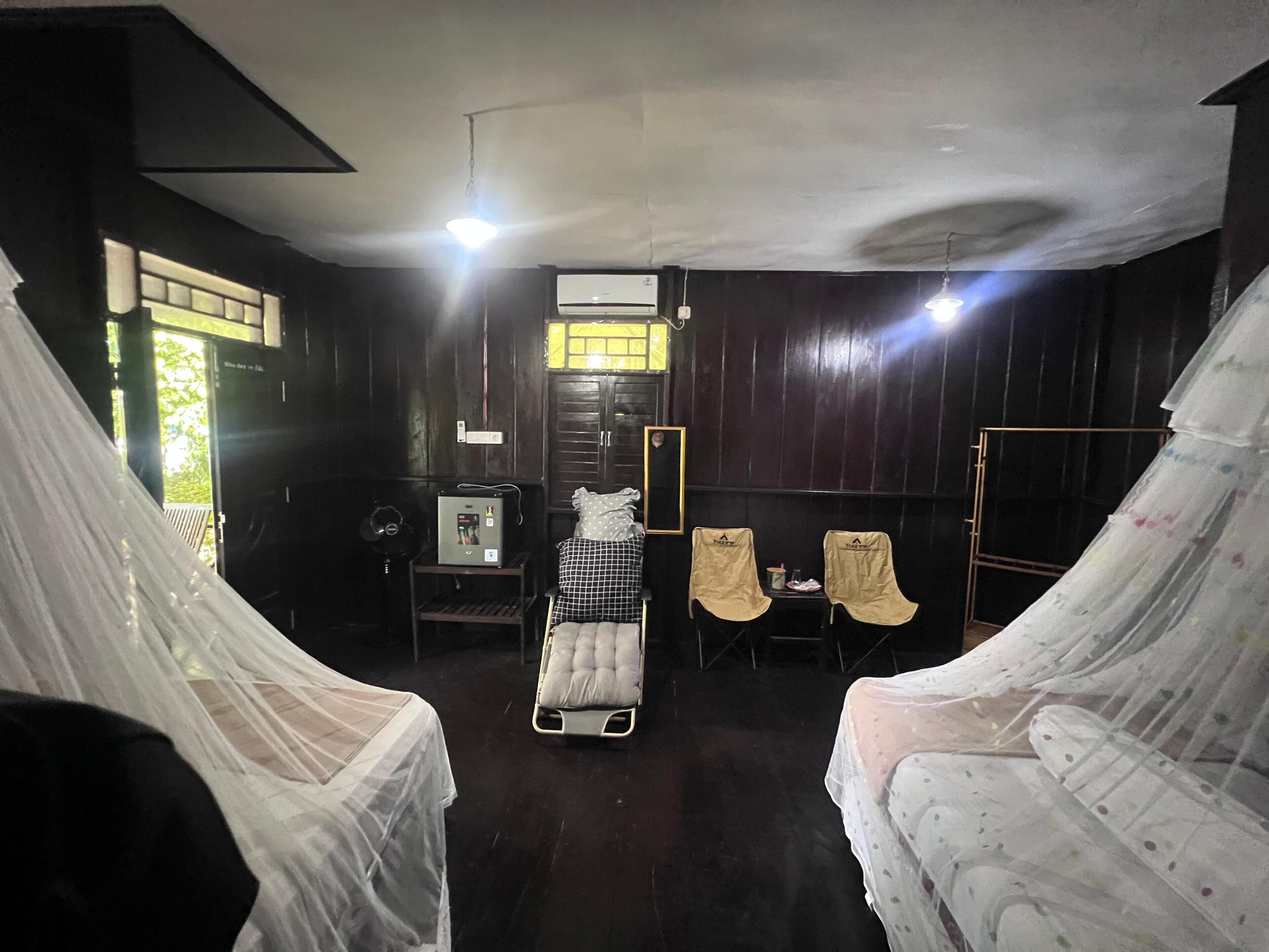 Une chambre avec deux lits, une petite table, un radiateur et une fenêtre.
