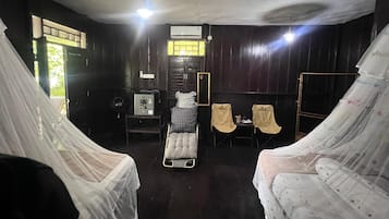 Une chambre avec deux lits, une petite table, un radiateur et une fenêtre.