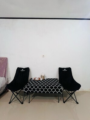 A small room with a white wall, a black and white patterned table, and two black chairs. - Charming villa with 1 bedroom and AC, WiFi, in phenomenal Raja Ampat (RAJA AMPAT)