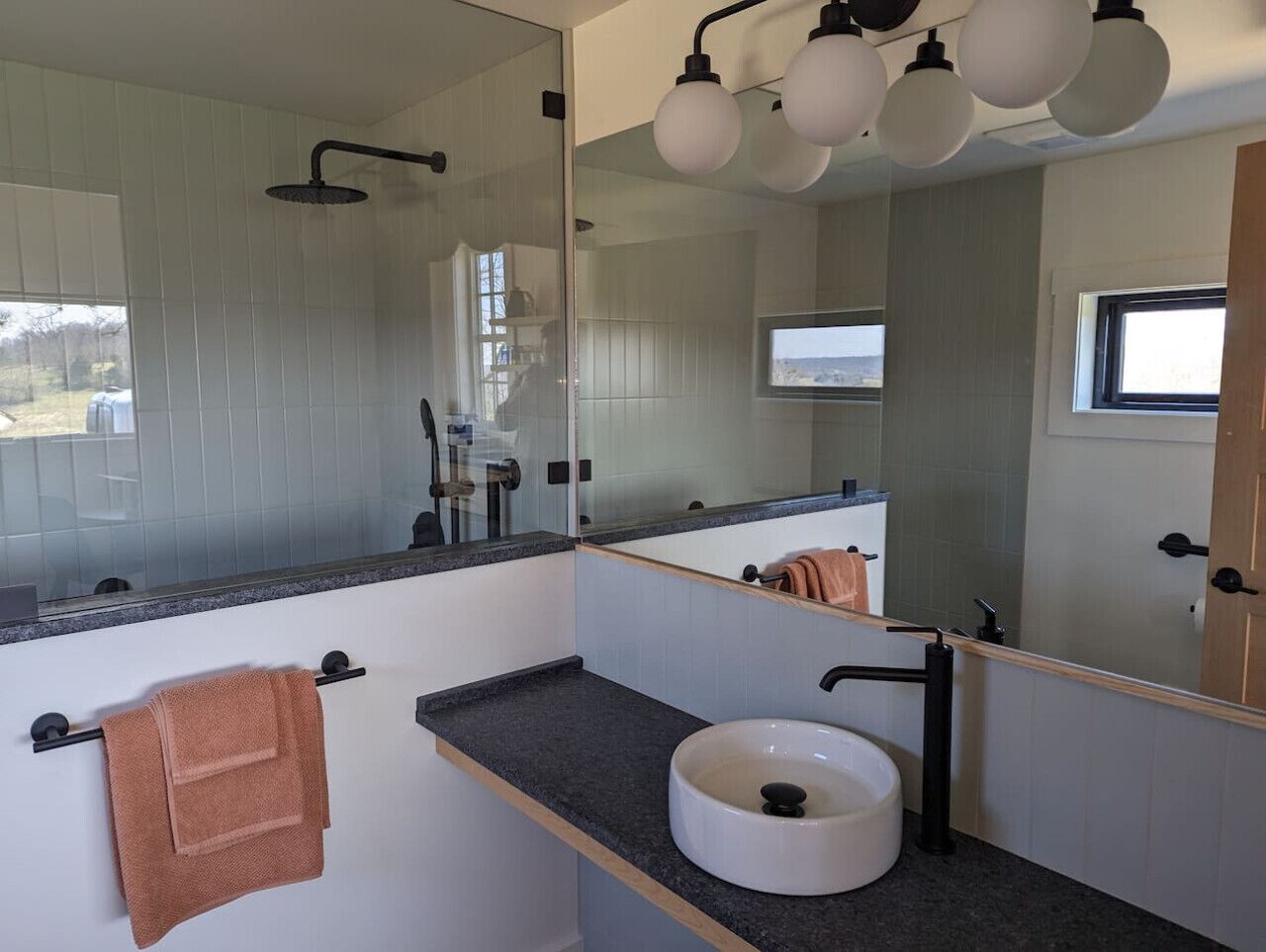 Un baño moderno con un espejo grande, un lavabo y un perchero para toallas.