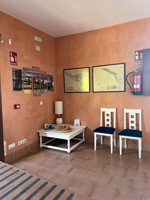 A room with a white table, two chairs, a lamp, and wall-mounted artwork. - Ikigai Albergue  (Navarrete)