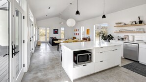 Une cuisine moderne avec des meubles blancs, un îlot central et des luminaires suspendus.