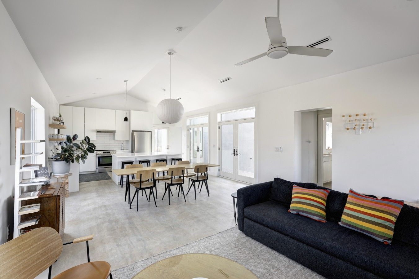 A modern living space with a dining area, a sofa, and a ceiling fan.