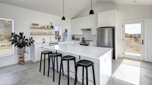 Une cuisine moderne dotée d’un grand îlot central, de tabourets de bar et d’un distributeur d’eau.