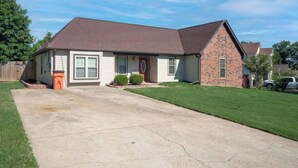 A single-story house with a brick section and a white facade, a front yard, and a driveway. - Newly Renovated "Home Away From Home"
A spacious, modernized 4-bedroom home. (Brighton)