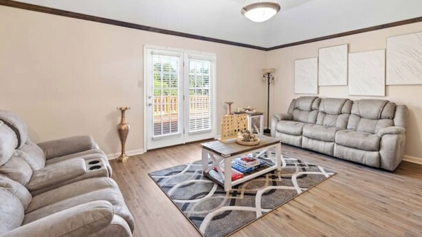 A living room with a sofa, a coffee table, and a floor lamp. There are two doors leading outside. - Newly Renovated "Home Away From Home"
A spacious, modernized 4-bedroom home. (Brighton)