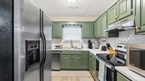 A kitchen with green cabinets, a stainless steel refrigerator, a microwave, and an oven. - Newly Renovated "Home Away From Home"
A spacious, modernized 4-bedroom home. (Brighton)