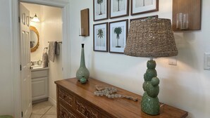 A hallway with a wooden dresser, a green vase, and a wall-mounted lamp. - 3-bedroom, 1st floor condo in charming South Padre Island, 3 min walk to beach (South Padre Island)