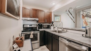 A modern kitchen with stainless steel appliances, wooden cabinets, and a large window with a view. - Snowater Condo 45sw With a Media Room (Deming)