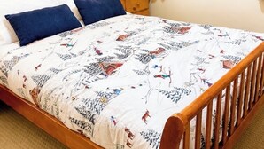 A bed with a patterned bedspread, a wooden headboard, a nightstand with a lamp, and a window with wooden shutters. - Red Mtn views, walk to lift, 2 bed, 2 bath condo. Fireplace! (Trail)