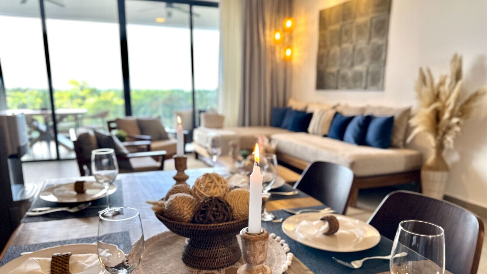 Un comedor con una mesa dispuesta para una comida, un centro de mesa con velas y vistas al exterior.