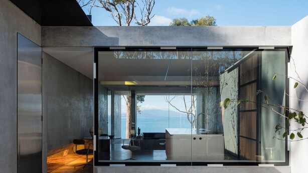 A modern interior with a large glass window, a minimalist design, and a view of the sea. - Vipp Tunnel - Tasmania (Apollo Bay)