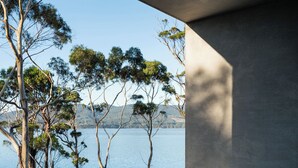 A modern architectural structure with a concrete exterior and a view of a lake with trees. - Vipp Tunnel - Tasmania (Apollo Bay)